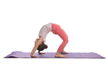 A young girl performing a yoga pose on a purple mat, showcasing flexibility and balance to reduce gymnastics injury risks.