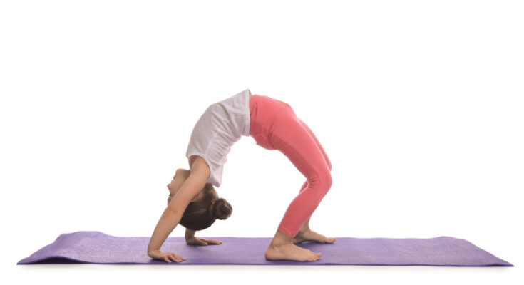 A young girl performing a yoga pose on a purple mat, showcasing flexibility and balance to reduce gymnastics injury risks.